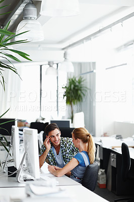 Buy stock photo Two colleagues talking while working on the computer in the office