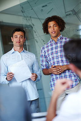 Buy stock photo Two attractive casual businessmen giving a presentation using a glass window for demonstration