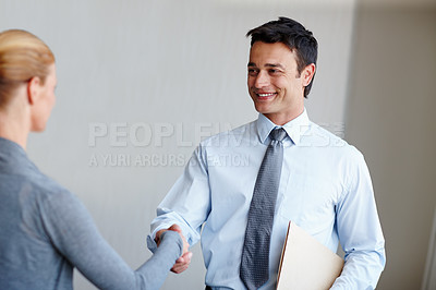 Buy stock photo A young businessman shaking hands with a female coworker