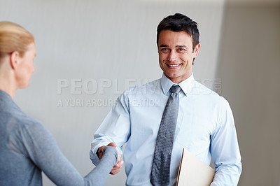 Buy stock photo A young businessman shaking hands with a female coworker