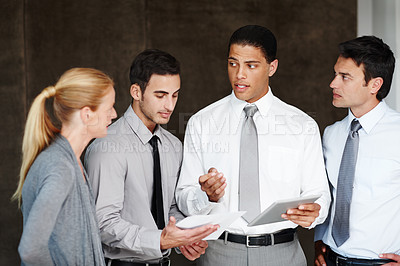 Buy stock photo Multi-ethnic group of businesspeople talking while using a digital tablet