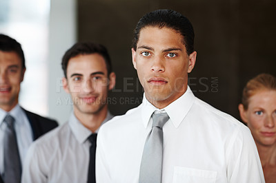 Buy stock photo An african american businessman looking at the camera with his coworkers in the background