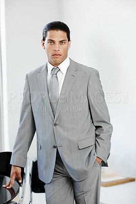 Buy stock photo Handsome businessman standing alongside a table