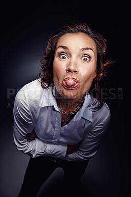 Buy stock photo Mocking, tongue out and face of woman with gesture isolated on dark background in studio. Rude, mean and portrait of person gesturing for comedy, naughty expression and backchat communication