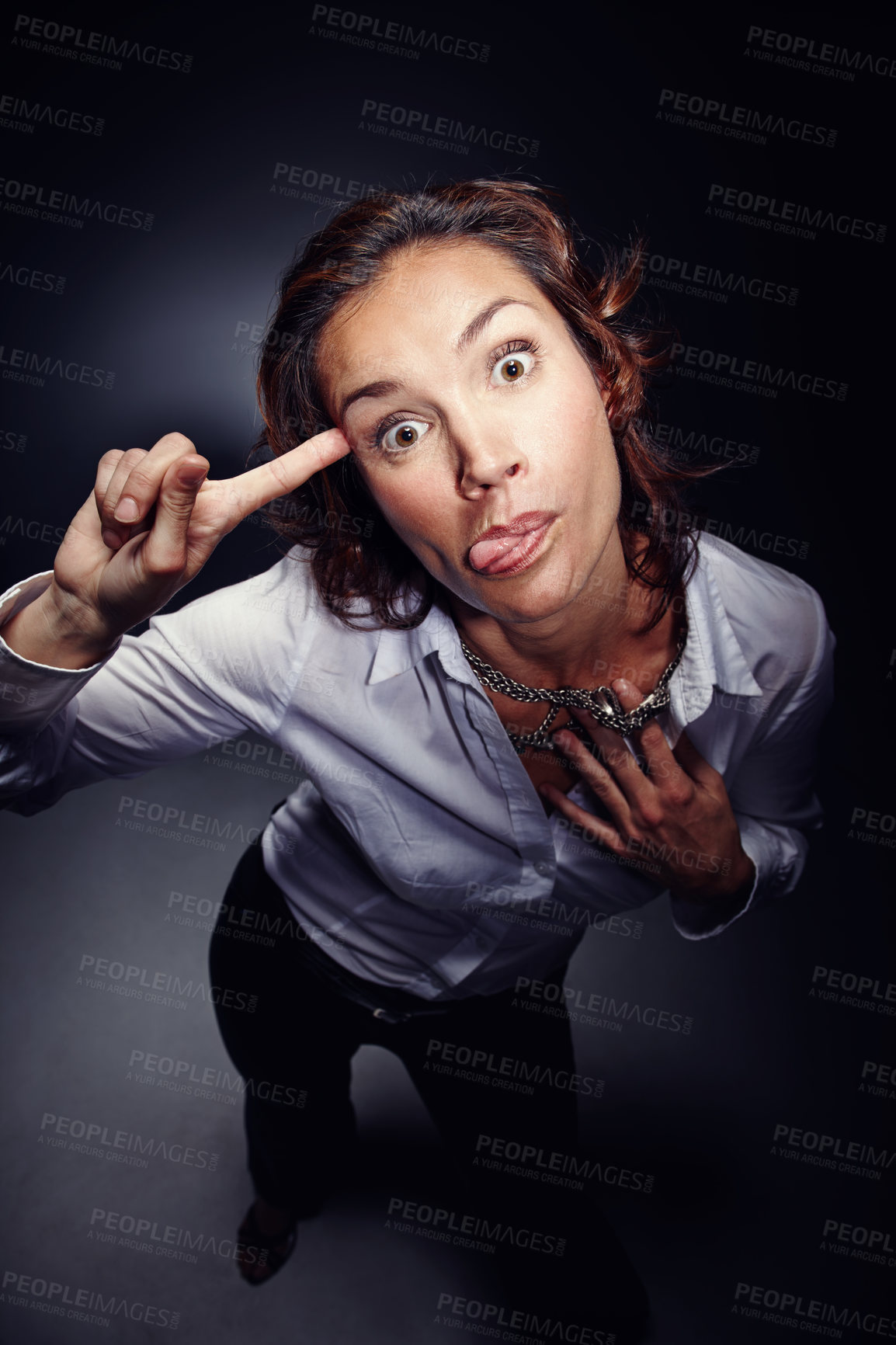 Buy stock photo Mocking, tongue out and face of woman with rude gesture isolated on dark background in studio. Funny, mean and portrait of person gesturing for talking, conversation and backchat communication