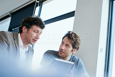 Buy stock photo Cropped shot of two handsome businessmen working on a digital tablet