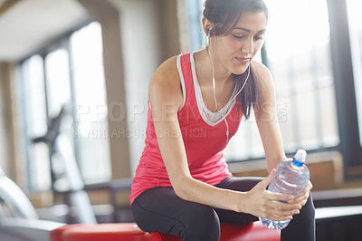 Buy stock photo Woman, water bottle and earphones in gym for workout, fitness and exercise for wellness. Training, energy and female person listening to music for self care, happiness and online for podcast 