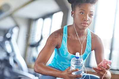 Buy stock photo Phone, headphones and black woman in gym with water, fitness app or playlist for music. Health, wellness and girl check social media on smartphone with bottle, break and relax in sports club.