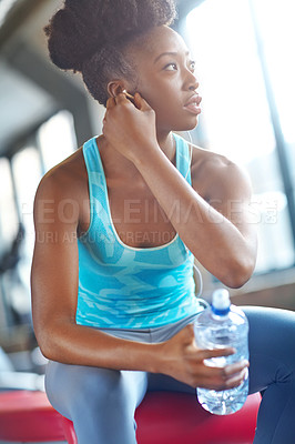 Buy stock photo Gym, earphones or black woman with water for fitness, break or body recovery after training. Listen, thinking or athlete with radio, music or podcast motivation for workout, exercise or sport routine