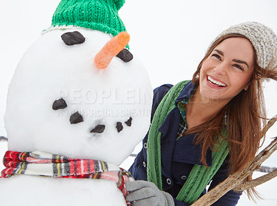 Buy stock photo Shot of an attractive young woman building a snowman