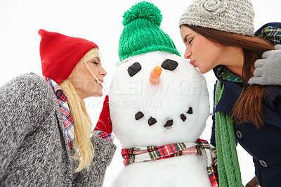 Buy stock photo Winter, friends and women kiss snowman enjoying holiday, vacation and festival tradition for Christmas. Nature, happiness and girls having fun, bonding and kissing ice figure outdoors in cold weather