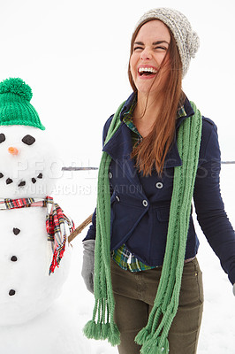 Buy stock photo Three quarter length shot of a young woman standing in front of a snowman