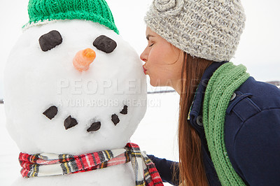 Buy stock photo Cropped shot of a beautiful young woman kissing a snowman