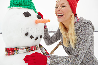Buy stock photo Cropped shot of a beautiful young woman building a snowman