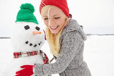Buy stock photo Cropped shot of a beautiful young woman building a snowman