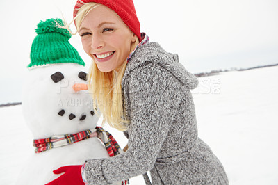 Buy stock photo Cropped shot of a beautiful young woman building a snowman