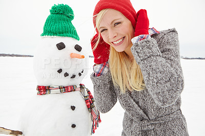 Buy stock photo Cropped shot of a beautiful young woman standing beside a snowman