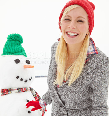 Buy stock photo Cropped shot of a beautiful young woman standing beside a snowman