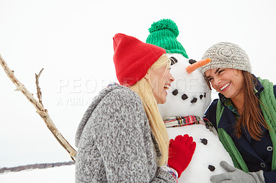 Buy stock photo Cropped shot of two young women building a snowman