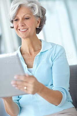Buy stock photo Shot of a happy senior woman using a digital tablet on the sofa at home