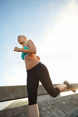 Buy stock photo Low angle shot of an attractive young woman out on her morning run