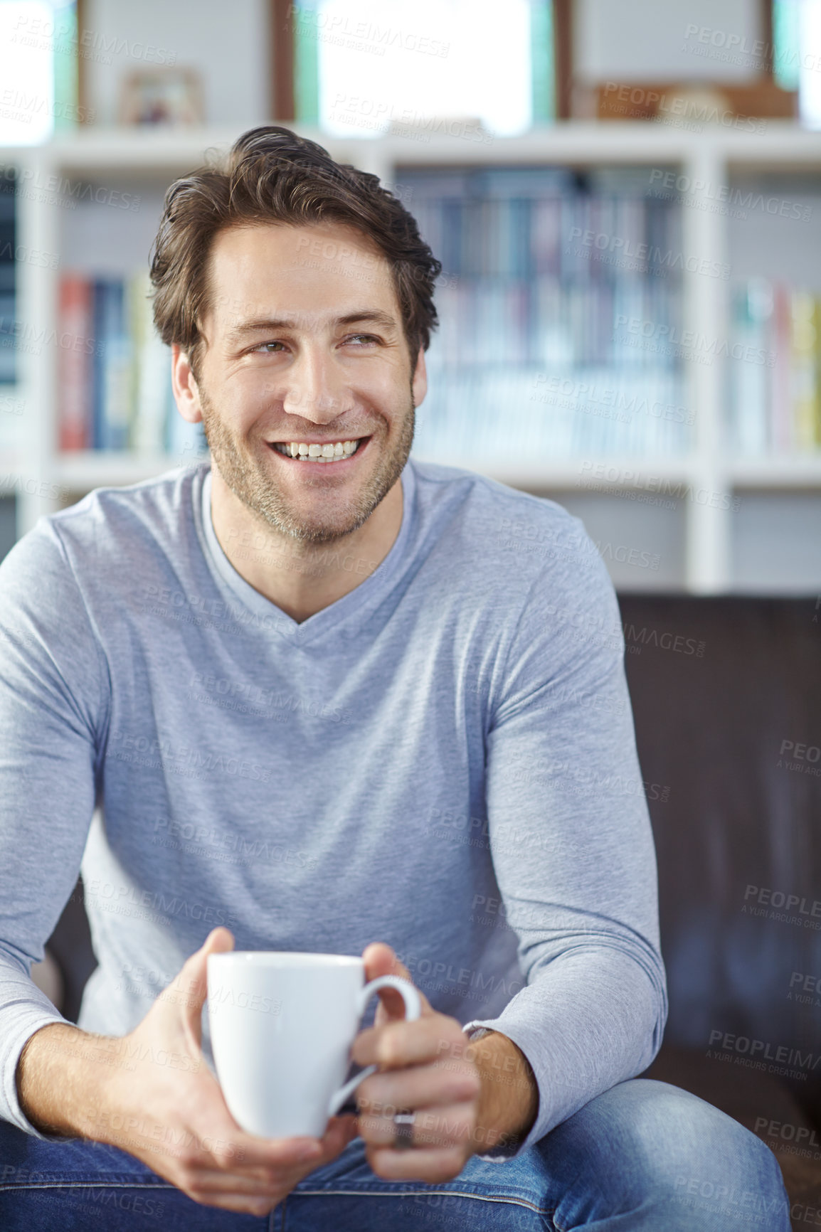 Buy stock photo One handsome smiling man sitting alone on his sofa in his living room and drinking coffee. Mature man feeling happy while drinking a cup of tea. Relaxing on the couch in lounge at home on a weekend