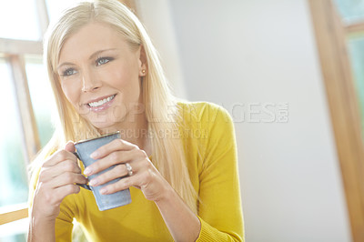 Buy stock photo A beautiful woman smiling and sitting near a window inside a house. Happy attractive blonde woman chilling drinking coffee. Happy female relaxing and daydreaming at home off the grid in a sunroom  