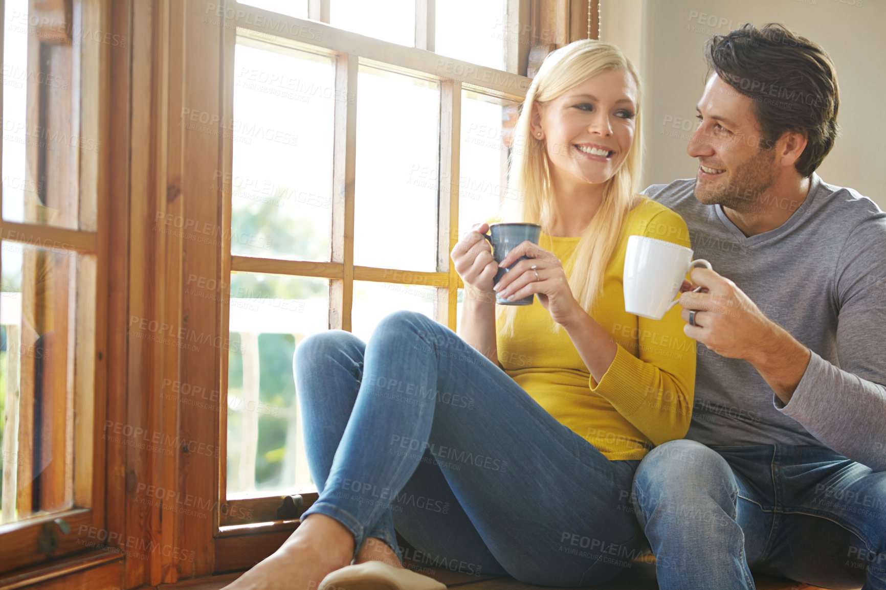 Buy stock photo Happy couple, relax and drinking coffee by home window for morning breakfast or caffeine, bonding or married. Man, woman and weekend resting in apartment or hotel vacation with smile, love or calm