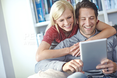 Buy stock photo Shot of an attractive young woman looking over her boyfriend's shoulder while he uses a digital tablet