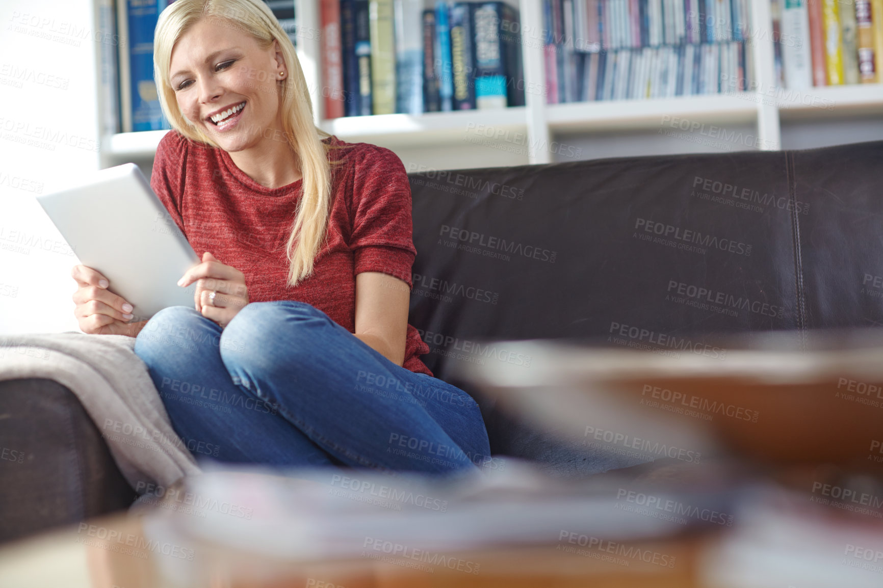 Buy stock photo Shot of an attractive young woman sitting on a couch while using a digital tablet