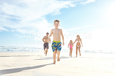 Buy stock photo Portrait of a happy little boy running ahead of his family at the beach