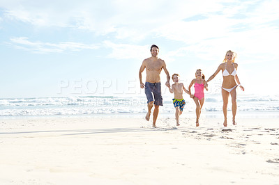 Buy stock photo Shot of a happy young family running on the beach together