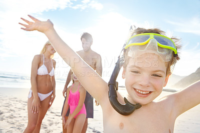 Buy stock photo Shot of a happy little boy wearing goggles while spending a day with his family at the beach