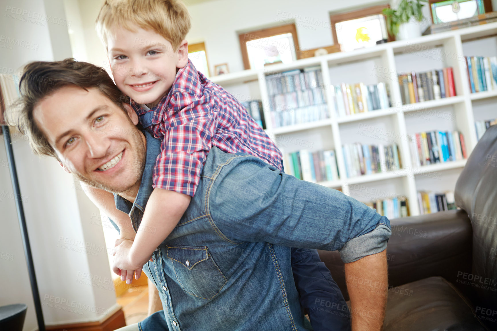 Buy stock photo Portrait, father and child on sofa with piggyback, bonding and love in living room for playful family in home. Relax, dad and son on couch for happy weekend together with fun, smile and embrace