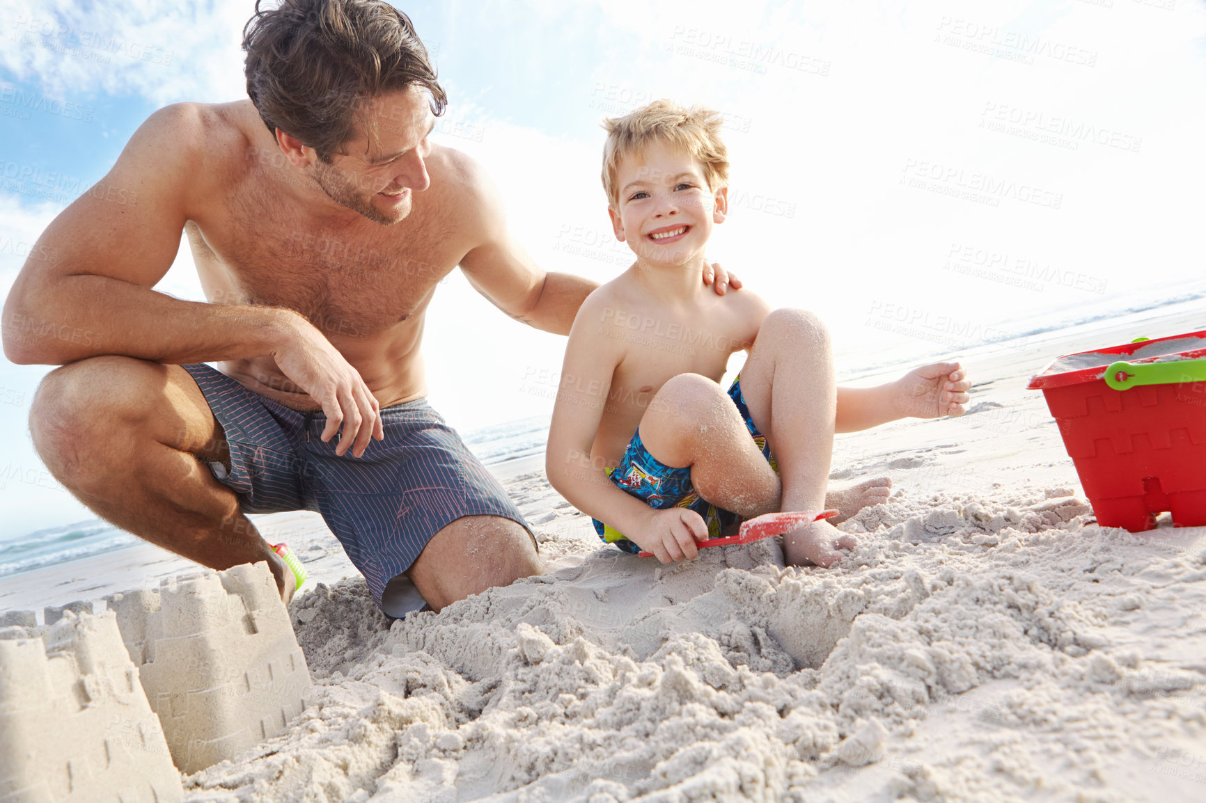 Buy stock photo Shot of a young father and son building a sandcastle on the beach