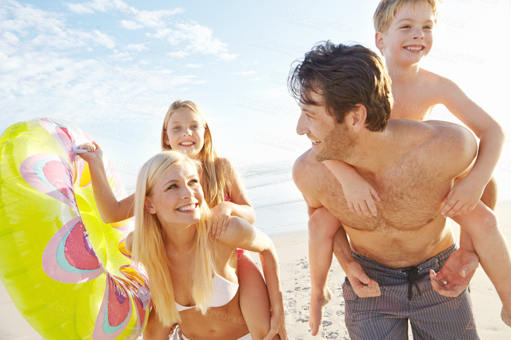 Buy stock photo Portrait, parents and kids with piggyback on beach for vacation, holiday and weekend trip in California. Outdoor, ocean and seaside with happy family, mom and dad with daughter or son for bonding