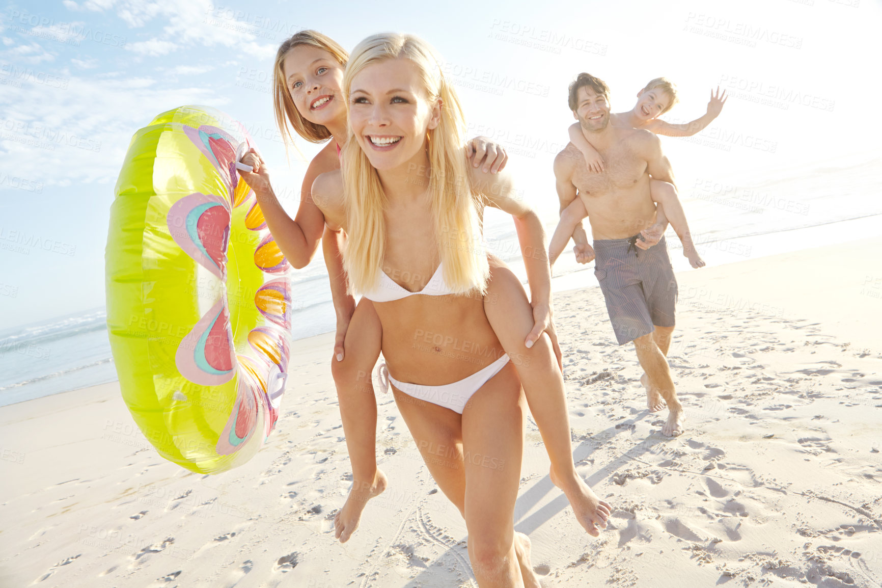 Buy stock photo Portrait, parents and children with piggyback on ocean for vacation, holiday and weekend trip in California. Outdoor, beach and seaside with happy family, mom and dad with daughter or son for bonding