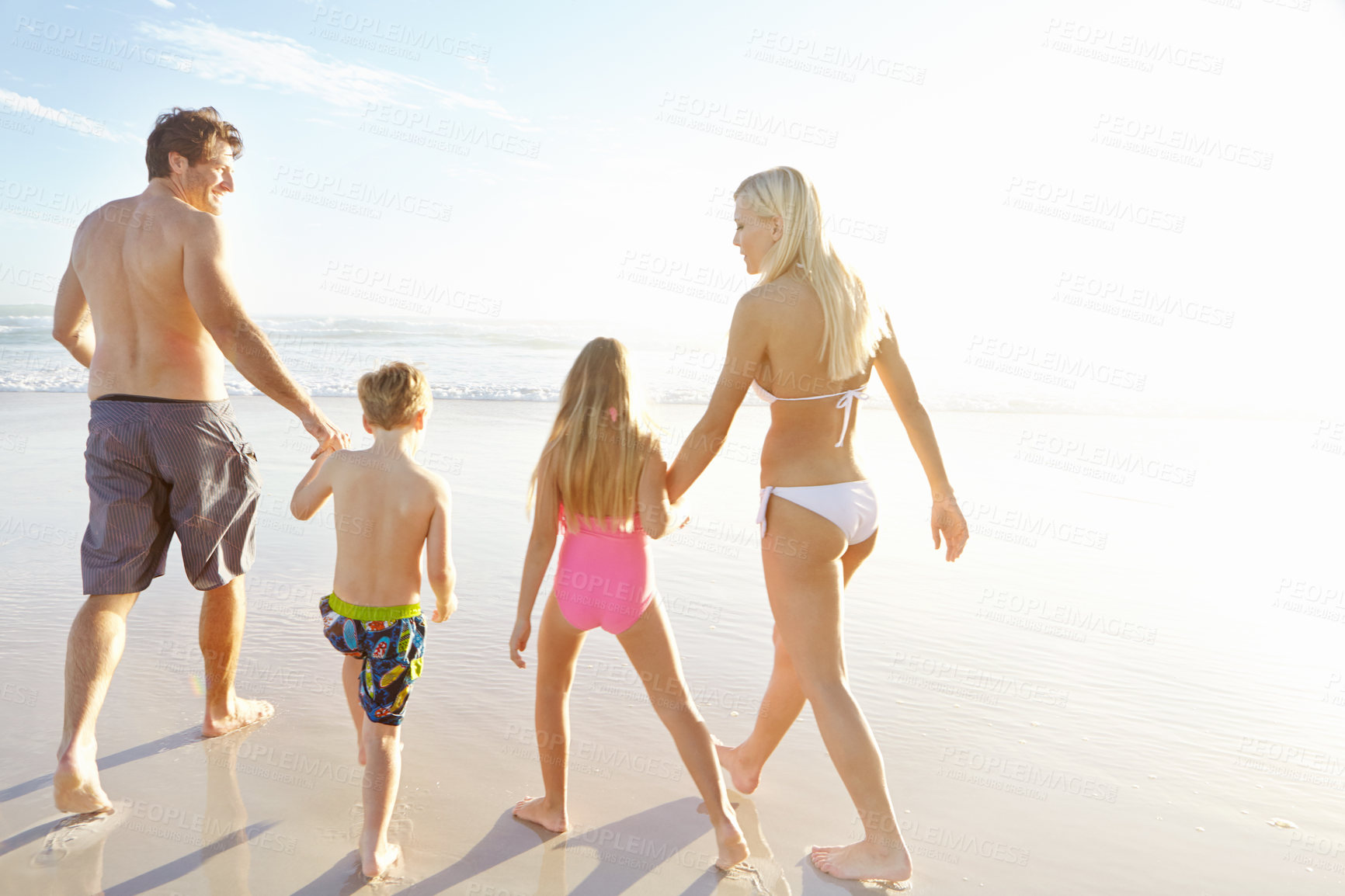 Buy stock photo Back, holding hands and sky with family on beach, walking together in summer for bonding or fun. Love, nature or smile with mother, father and kids on sand by ocean or sea for holiday and vacation