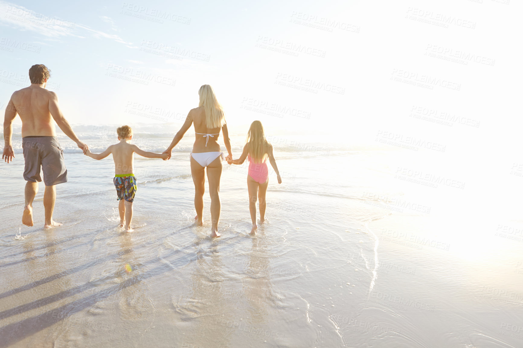 Buy stock photo Support, walking and family holding hands at a beach for summer, fun and bonding at sunset together. Travel, care and back of children with parents at sea for vacation, holiday or tropical adventure