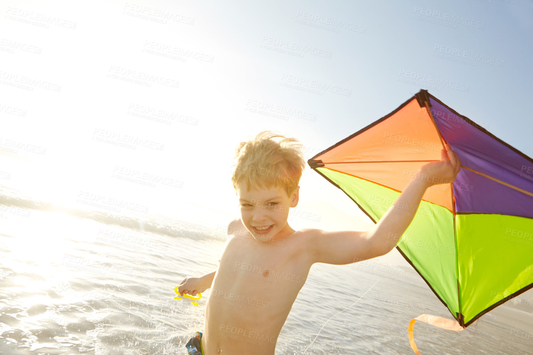Buy stock photo Boy, ocean and kite on beach with fun, adventure and playing in sunshine for summer holiday. Excited child or happy kid with game for fantasy, imagination and wind for travel or vacation in sea water