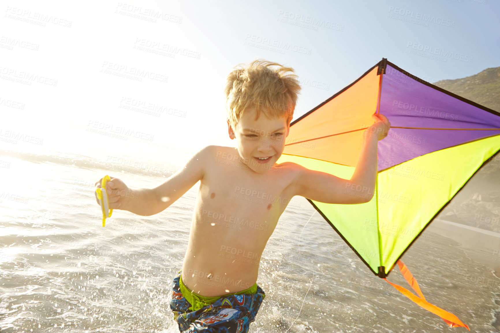 Buy stock photo Excited child, running and kite on beach with adventure, fun and playing in sunshine for summer holiday. Happy boy or kid splashing in sea water or waves with game and wind for travel or vacation