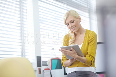 Buy stock photo Shot of an attractive young woman working on a digital tablet in an office