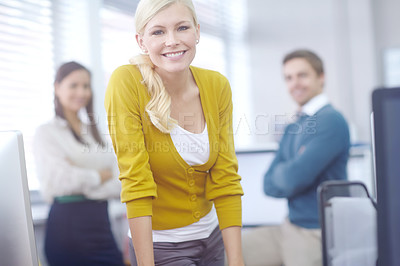 Buy stock photo Portrait of an attractive young blonde businesswoman with her colleagues in the background