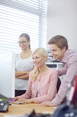 Buy stock photo Cropped shot of three young coworkers gathered around a single computer