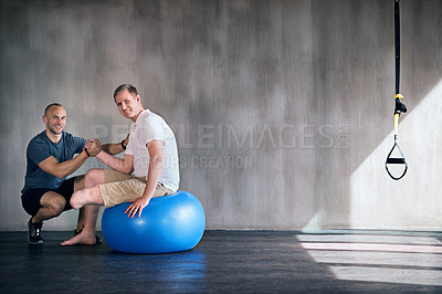 Buy stock photo Shot of a physiotherapist and his patient exercising on a swiss ball