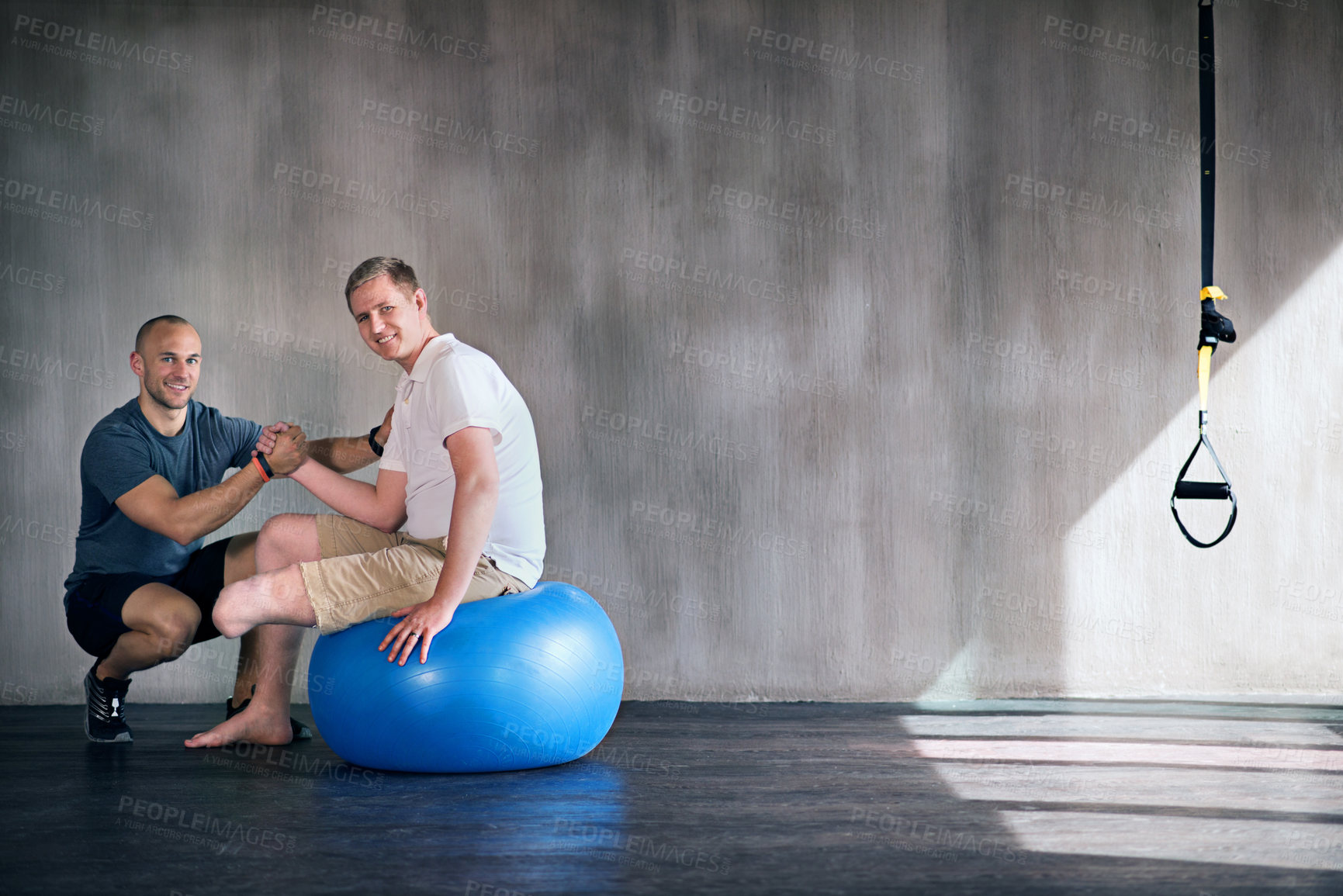Buy stock photo Shot of a physiotherapist and his patient exercising on a swiss ball