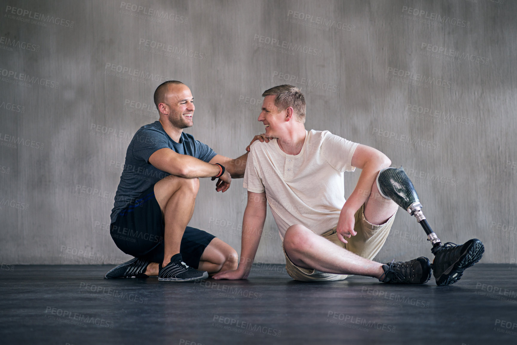 Buy stock photo Physiotherapist, man with a disability and prosthetic leg and laughing in physiotherapy, studio and sportswear. Male people, trainer and amputee fitness for wellness or exercise in sports center