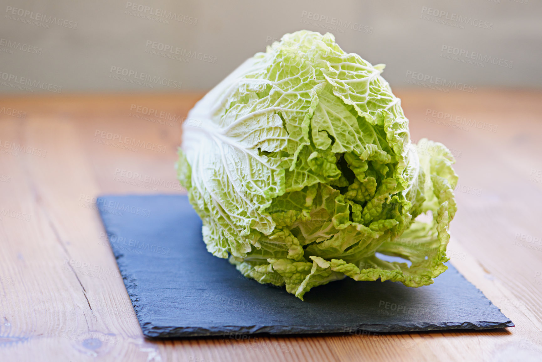 Buy stock photo Green vegetable, fresh and cutting board in kitchen for diet, cooking and wellness. Cabbage, whole and natural produce for food, nutrition and vegan in house for salad leaves, food and gut health.