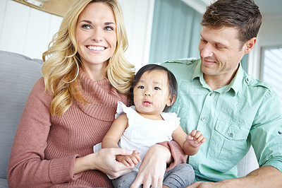 Buy stock photo Love, happy family and foster baby in home for care, support or bonding together. Mother, father and cute adopted kid with parents for connection, diversity or interracial with toddler in living room