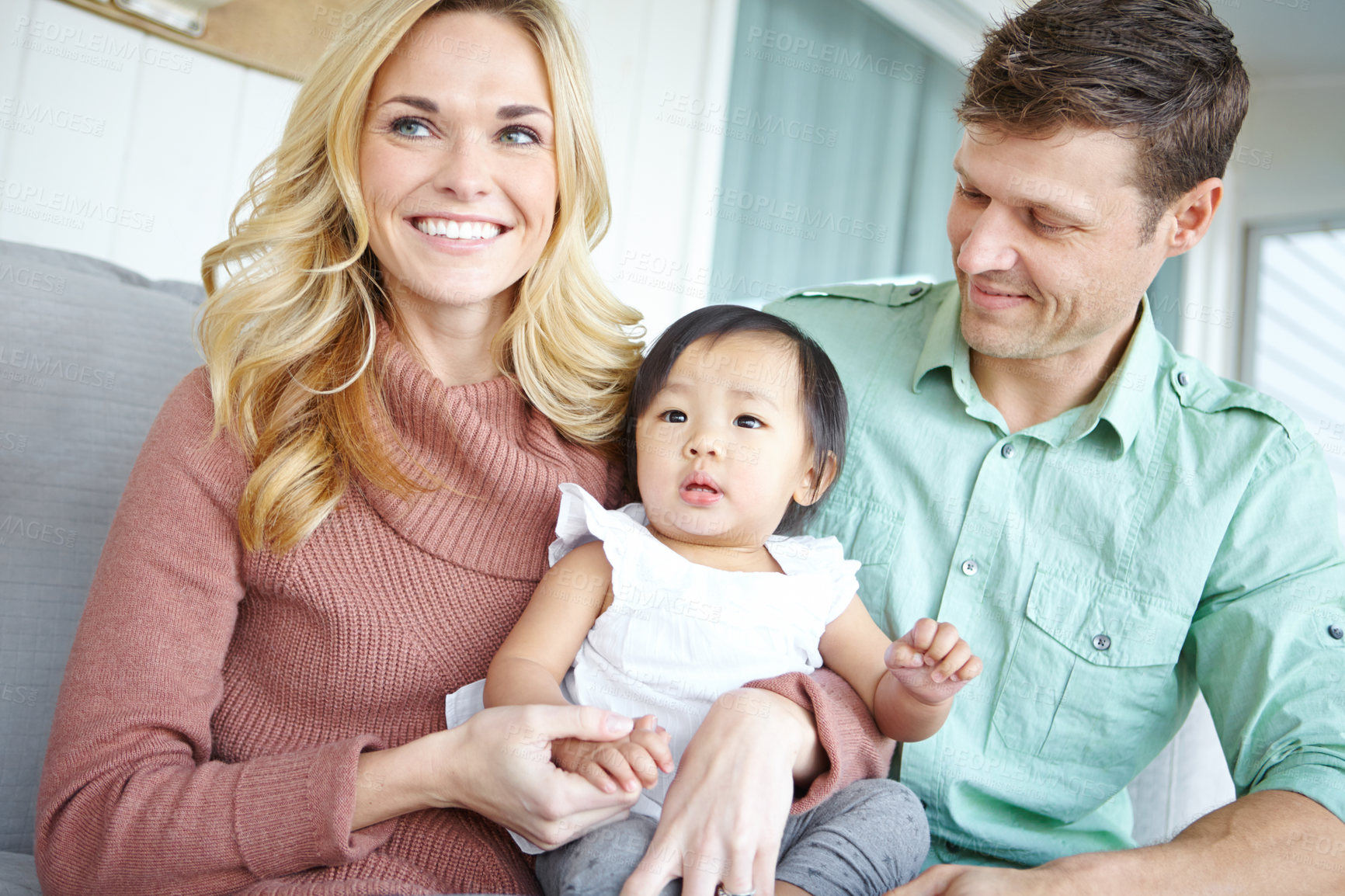 Buy stock photo Love, happy family and foster baby in home for care, support or bonding together. Mother, father and cute adopted kid with parents for connection, diversity or interracial with toddler in living room